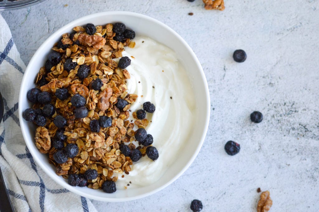 vegan blueberry trail mix in a white bowl with green yogurt and freeze dried blueberries