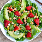 strawberry and basil salad with chickpeas, cheese and nuts on a white plate