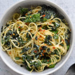 spaghetti with ricotta, kale and lemon in a white bowl