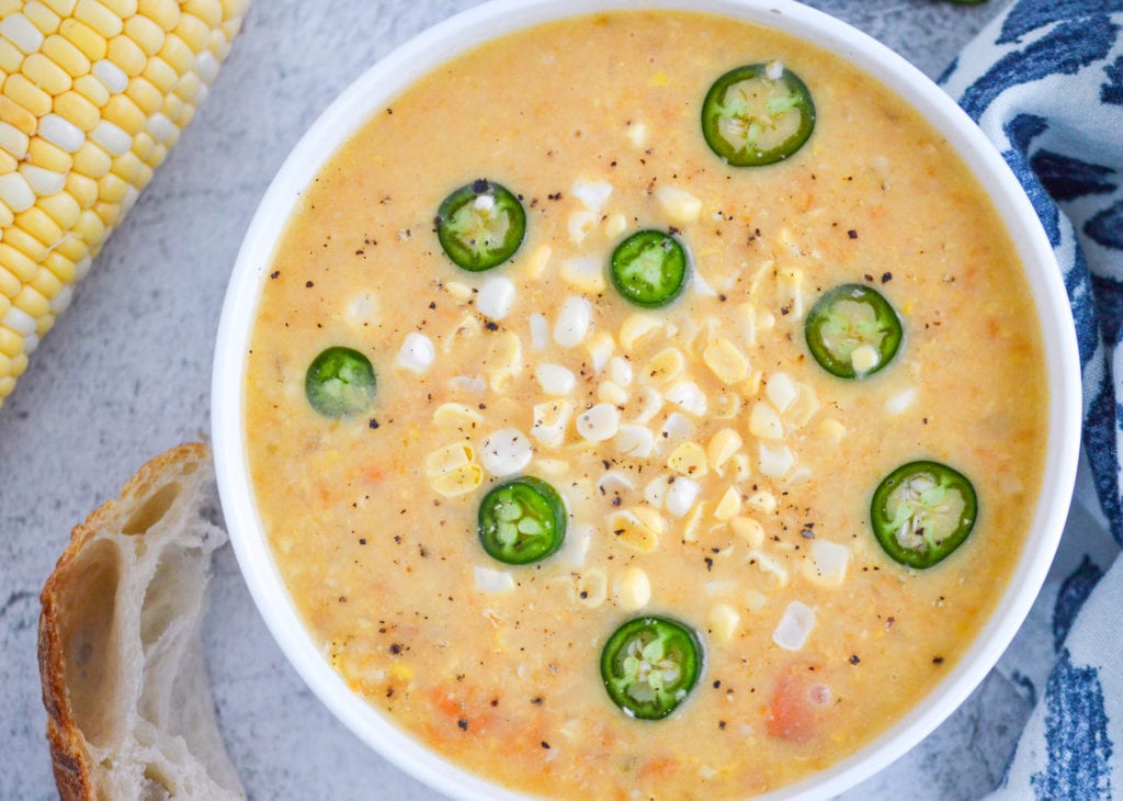 creamy vegetarian corn chowder in white bowl with bread