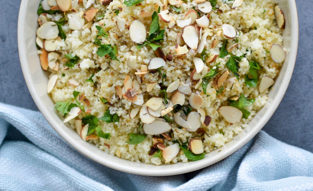 couscous with parsley, sliced almonds and zaatar vinaigrette in a white bowl