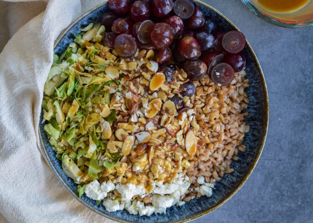 farro salad with feta, sliced almonds, red grapes and sliced brussels sprouts, topped with maple vinaigrette