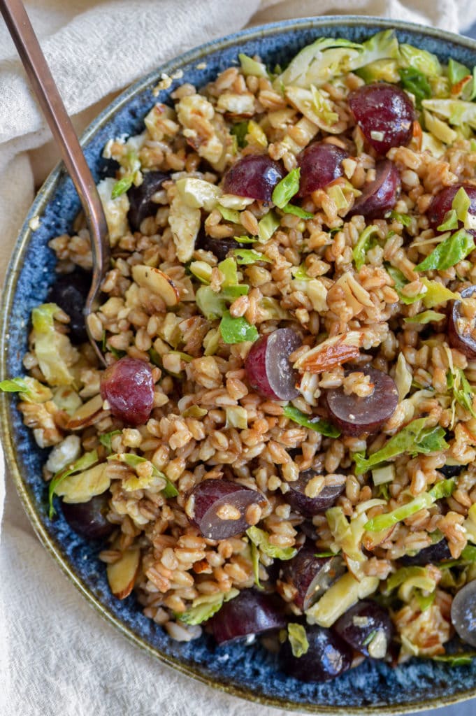 tossed farro salad with feta, sliced almonds, red grapes and sliced brussels sprouts, topped with maple vinaigrette