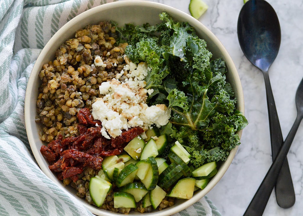 lentils in a bowl with sun dried tomatoes, kale, feta and cucumbers